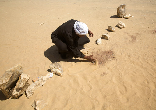 A  man covers the blood stains of victims on the road leads to St. Samuel