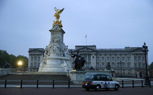 A London black taxi drives past the Queen Victoria Memorial outside Buckingham Palace