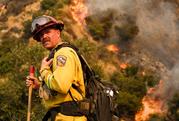 A crew member with California Department of Forestry and Fire Protection (Cal Fire) battles a brushfire on the hillside in Burbank