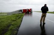 A passing motorist stops to look at a flipped truck in the aftermath of Hurricane Harvey Saturday