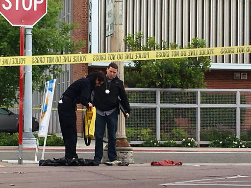 Fresno police stand next to a pile of clothes in front of a corner market in the neighborhood where shootings occurred in Fresno