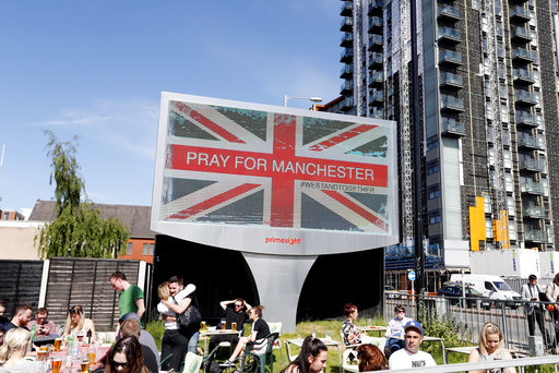People sit under a billboard in Manchester city centre