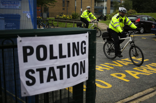Police officers ride away on their bikes after inspecting the polling station for Britain's general election