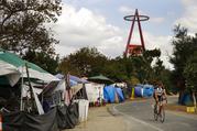 A cyclist passes the row of tents and tarps along the Santa Ana riverbed near Angel Stadium Thursday