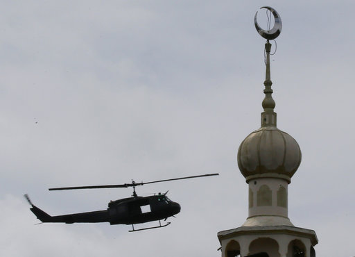 A military helicopter hovers by a mosque as government troops battle with Muslim militants who continue to hold their ground in some areas of Marawi city for almost a week Monday