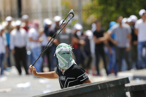 A Palestinian uses a slingshot against Israeli soldiers during clashes in the West Bank city of Bethlehem