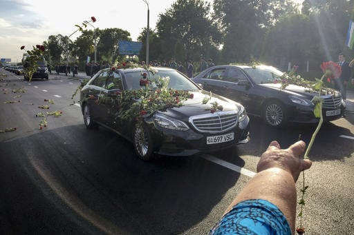People throw flowers on limousines as they gather along a road to watch the funeral procession of President Islam Karimov in Tashkent
