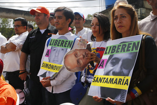 Relatives of jailed opposition leaders hold posters asking for the liberation of their loved ones outside the Ramo Verde military prison in Los Teques
