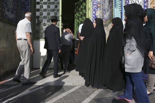 Iranian voters enter a polling station to vote for the presidential and municipal councils election in Tehran