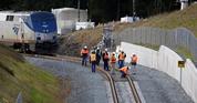 Workers look over tracks near the rear car of a crashed Amtrak train that remains standing where the southbound tracks make a curve left Tuesday