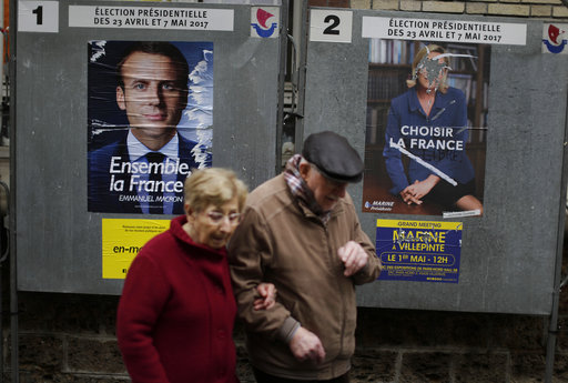 People walk past election posters near a polling station in Paris