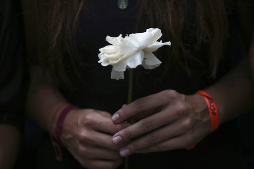 A protester carries a white flower during a silent protest in homage to the at least 20 people killed in unrest generated after the nation's Supreme Court stripped congress of its last powers