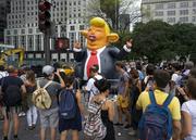 An inflatable caricature of President Donald Trump rises above pedestrians at W. 59th Street and 5th Ave. in New York Monday
