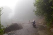 Neighbors walk under the rain past a washed out road in Alajuelita on the outskirts of San Jose