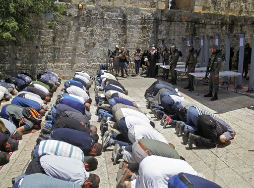 Israeli border police officers stand guard as Muslim men pray outside the Al Aqsa Mosque compound