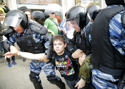 A young demonstrator is apprehended by riot police during a demonstration in downtown Moscow