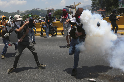 An anti-government protesters is hit by a tear gas grenade launched by security forces in Caracas