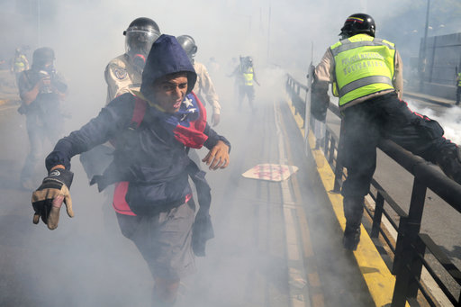 A protester tries to flee government security forces during a demonstration by opponents of President Nicolas Maduro who gathered to block a major highway in Caracas