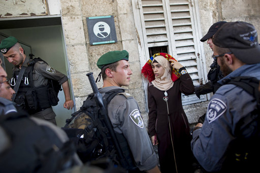Israeli border police officers stop a Palestinian woman for a security check as Palestinians gather for prayer at the Lion's Gate