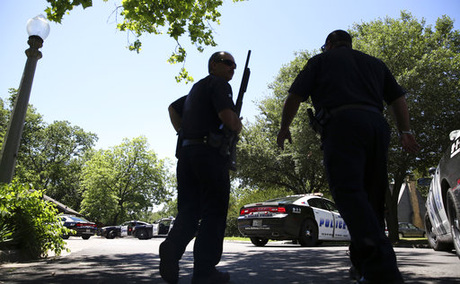 Dallas Police walk a neighborhood a block away from a shooting in Dallas