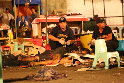 Philippine police investigators check bodies at a blast site at a night market that has left at least several people dead and wounded others in southern Davao city
