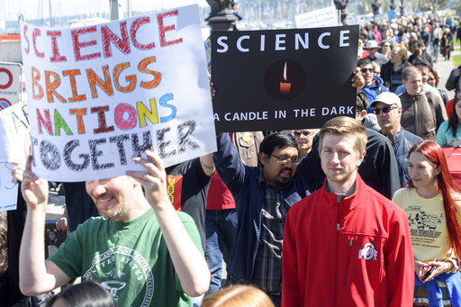 People stand together holding placards during the March for Science day in Geneva