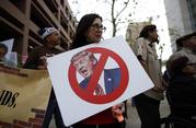 Jill Green holds a sign during a rally against a scheduled upcoming visit by President Donald Trump