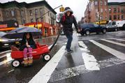 Astrid Fernandez gives her daughter Hailie a ride through the rain on the way to school