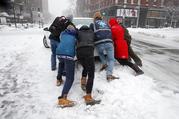 People push a stranded taxi during a snowstorm