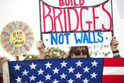 Lauren Rees holds up a sign during a rally against a upcoming scheduled visit by President Donald Trump Tuesday