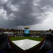 Grounds crew workers pull the tarp off the field after a storm dumped rain on Kauffman Stadium before a baseball game between the Kansas City Royals and the Los Angeles Angels
