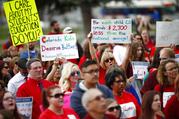 Teachers hold placards during a rally outside the state Capitol