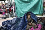 A girl who traveled with the annual caravan of Central American migrants awakens where the group set up camp to wait for access to request asylum in the U.S.