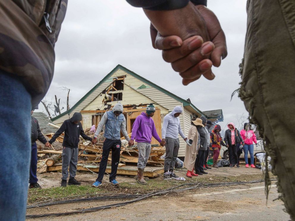 PHOTO: Residents of Talbotton, Ga., pray together outside a home destroyed by a tornado the day after storms battered Alabama and Georgia, March 4, 2019.