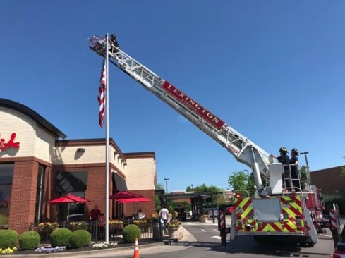 Lexington firefighters replacing a damaged American flag at Chick fil A