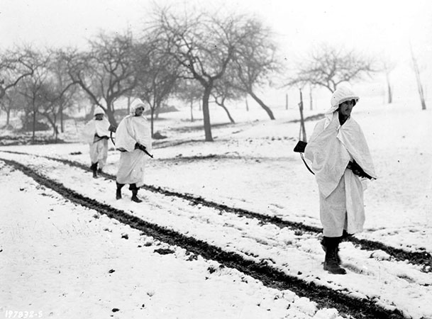 Three members of an American patrol cross a snow-covered Luxembourg field on a scouting mission