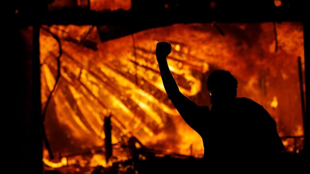 A protester gestures in front of the burning 3rd Precinct building of the Minneapolis Police Department on Thursday
