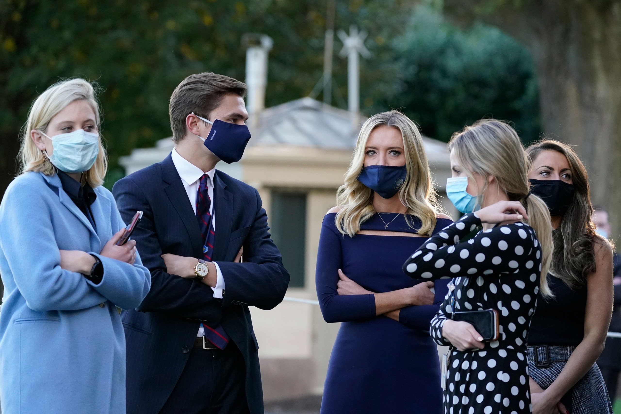 White House press secretary Kayleigh McEnany, third from left, waits with others as President Donald Trump prepares to leave the White House to go to Walter Reed National Military Medical Center on October 2 in Washington, DC.