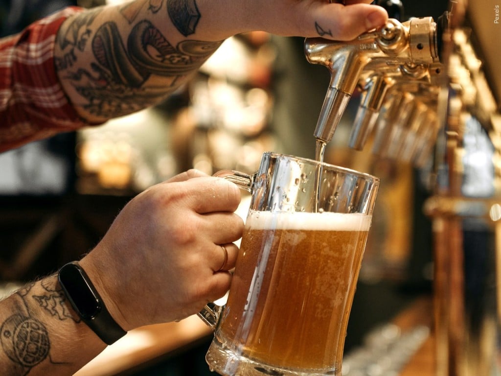 Person pouring beer on tap