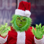 A Person Dressed As The Grinch In Times Square Poses For Photos In New York