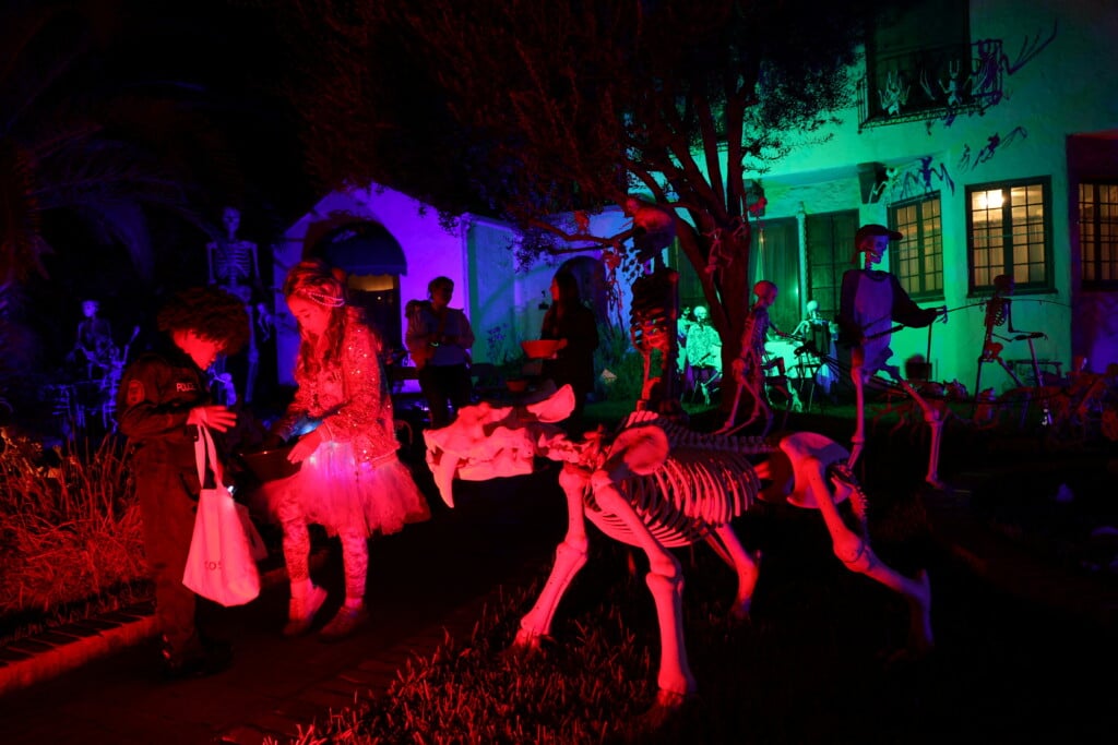 Kids Go Trick Or Treating At A Decorated House On Halloween Night In Pasadena, California