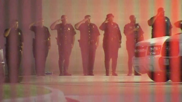 Dallas Police officers standing outside Parkland Hospital, saluting their fallen brethren. (Photo: WFAA)
