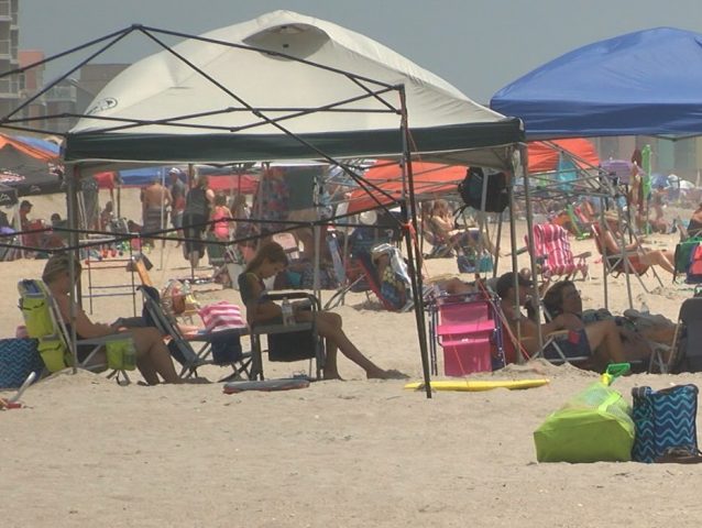 Tents and umbrellas fill a beach strand. (Photo: WWAY)