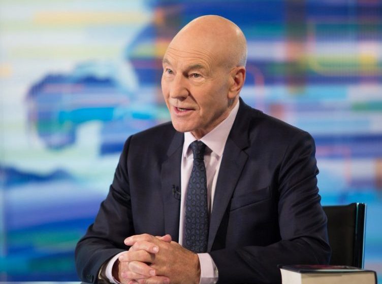 Patrick Stewart sitting at desk Patrick Stewart suit Patrick Stewart applying for citizenship