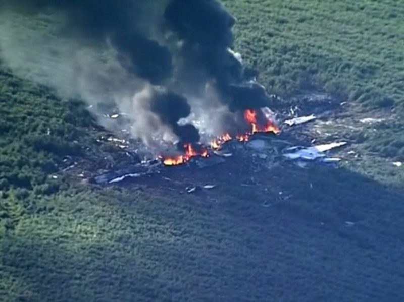 The wreckage of a military aircraft burns after crashing in a field near Greenwood