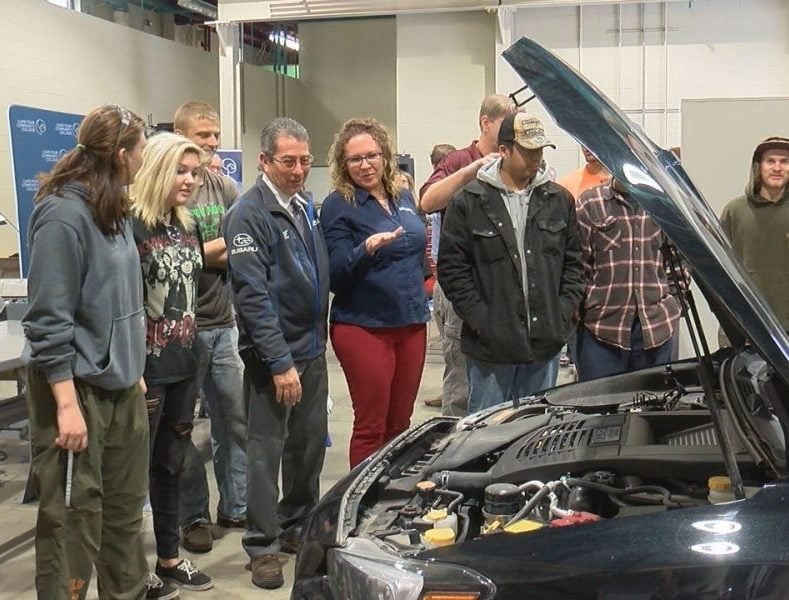 A representative of Subaru showing the students the engine of the car the students will get to work with on December 5