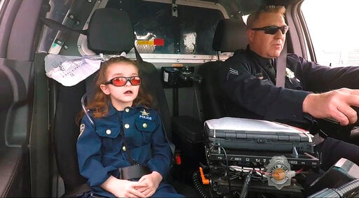 In this image from an April 2017 video provided by the Denver Police Department, Olivia Gant, who was 6 years old at the time, rides with Capt. Tim Scudder on a call in Denver.