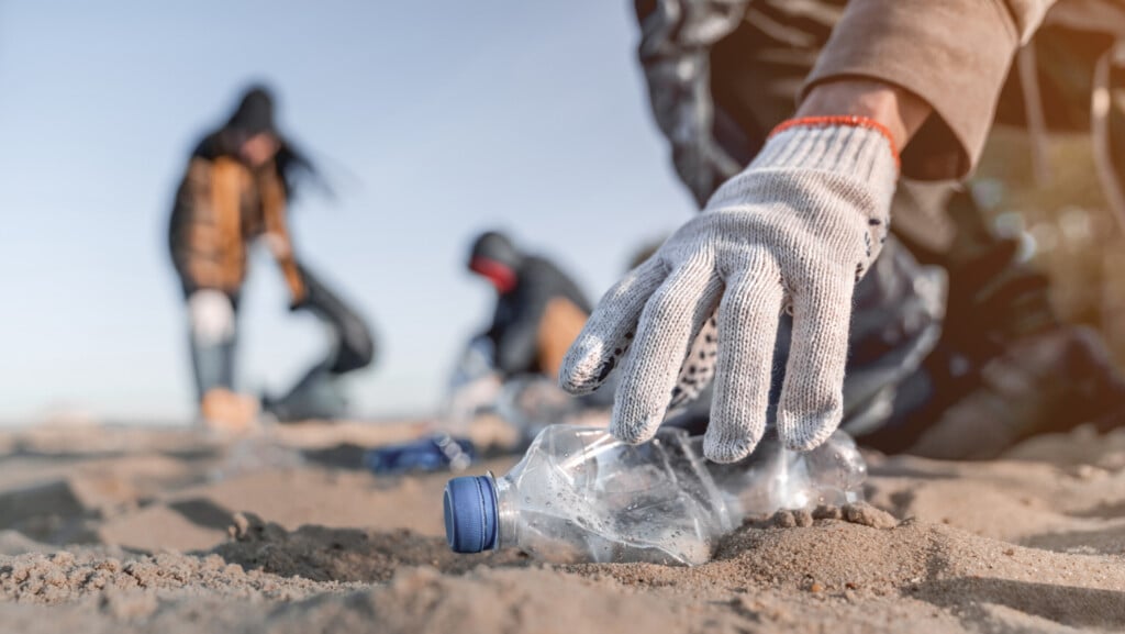 Volunteer Man Collecting Trash On The Beach. Ecology Concept