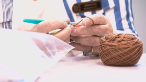 A person works on a "knitted knocker," a crocheted or hand-knitted breast prosthetic.