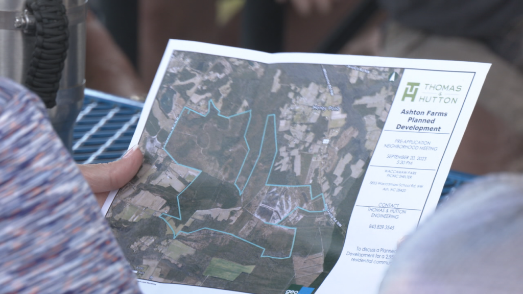 A citizen holds a map of the proposed development, "Ashton Farms."